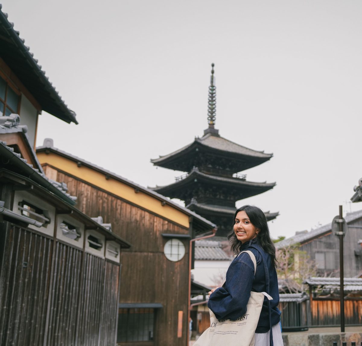 Anmol smiling over her shoulder on a Kyoto street, with a pagoda behind her